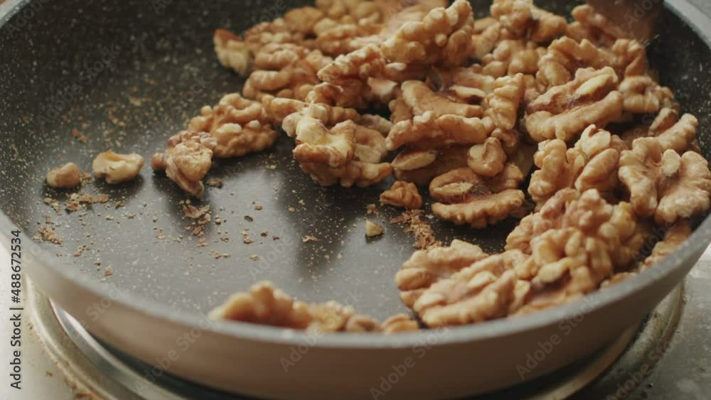 Anonymous person frying walnuts in pan in kitchen Anonymous person frying walnuts in pan in kitchen