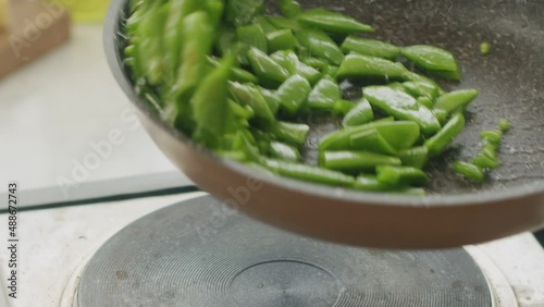 Unrecognizable cook frying green beans in pan photo