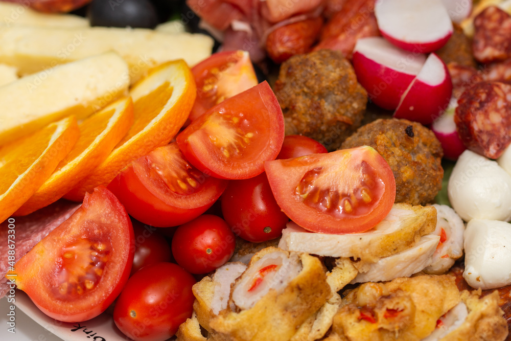 plate with vegetables and fruits., oranges, tomatoes, cheese, grapes, sausages plate with vegetables and fruits., oranges, tomatoes, cheese, grapes, sausages