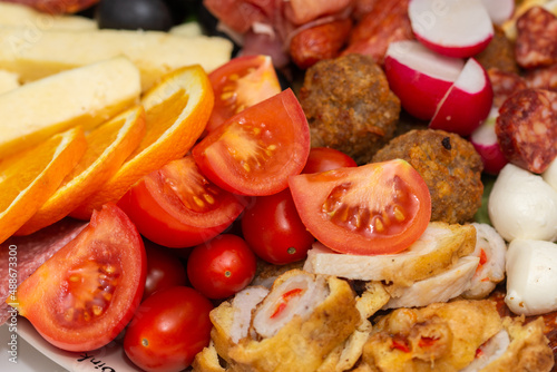 plate with vegetables and fruits., oranges, tomatoes, cheese, grapes, sausages 