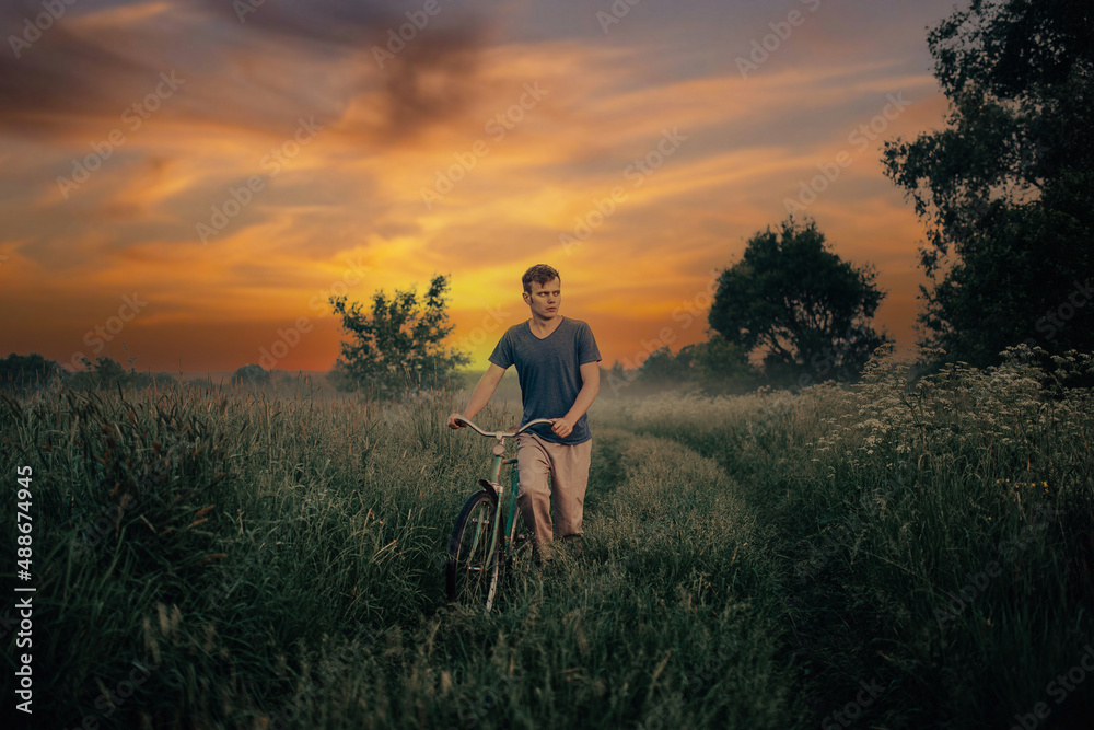 young man walks with a retro bicycle along a field road at sunset, an art photo of a lonely man.