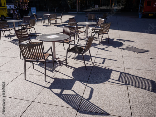 round tables and chairs in the open-air cafeteria and its shadow on the ground in tokyo