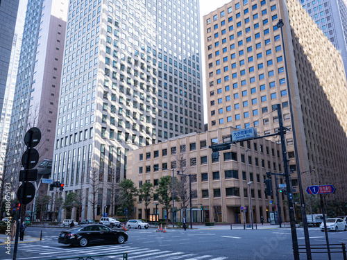 cityscape of business district in tokyo; office buildings and car crossing the cross road