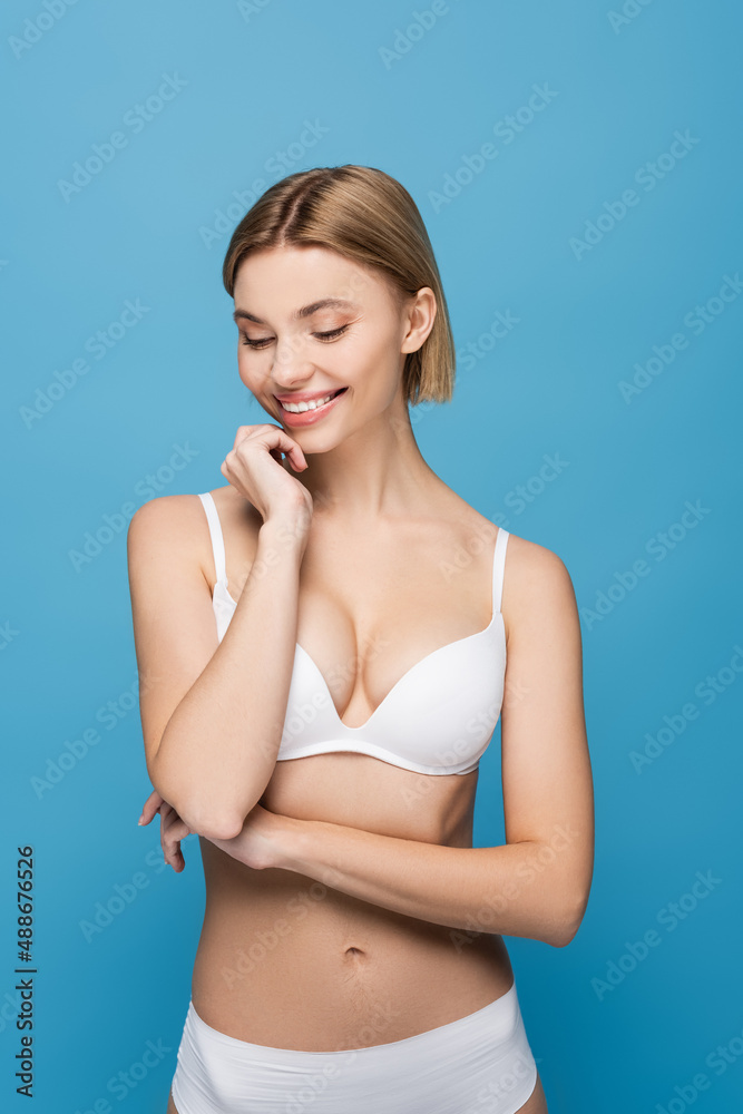 Fototapeta premium slim young woman in white underwear smiling isolated on blue