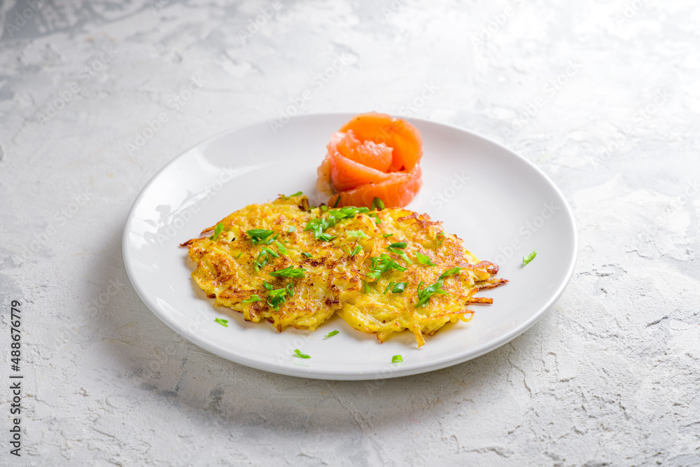 Fried potato pancakes with salted salmon on white plate Fried potato pancakes with salted salmon on white plate