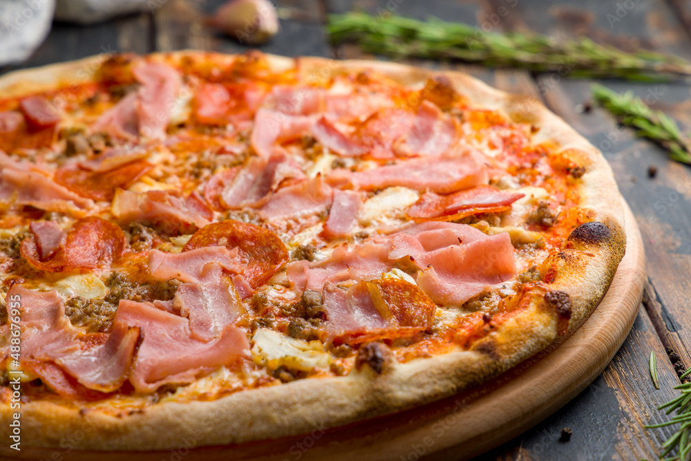 Italian meat pizza with pepperoni, meat, ham and chicken with cheese on old wooden table macro close up Italian meat pizza with pepperoni, meat, ham and chicken with cheese on old wooden table macro close up