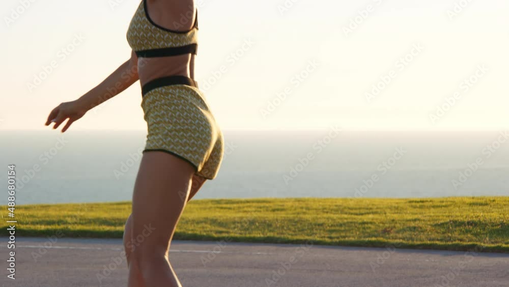 Beautiful, cheerful woman riding on roller skates at playground with scenic ocean view in the background. Professional female athlete during an outdoor workout by the beach. High quality 4k footage