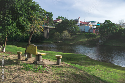 Bench at the river side with Hawkesworth suspension bridge crossing in San Ignacio, Belize photo
