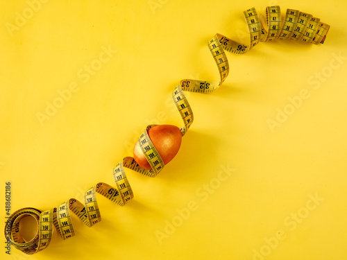 golden easter egg and yellow tape measure on yellow background. Healthy nutrition for weight loss, fitness and composition with copy space. Diet concept. Top view from above, flat lay,