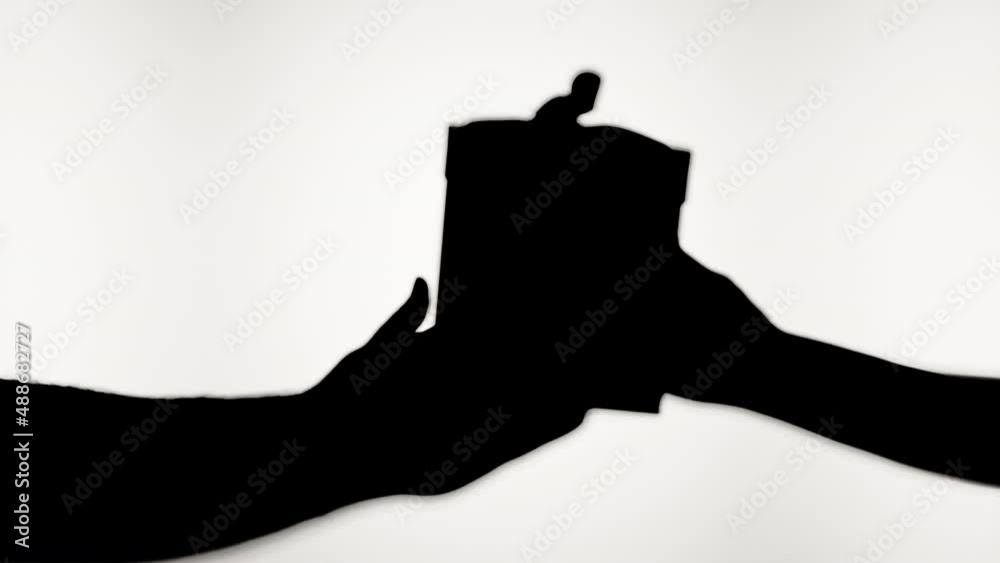Shadow of giving present on white background. Taking gift box close-up silhouette. Happy Valentine`s day and love relationships concept, celebrating holiday, birthday party.