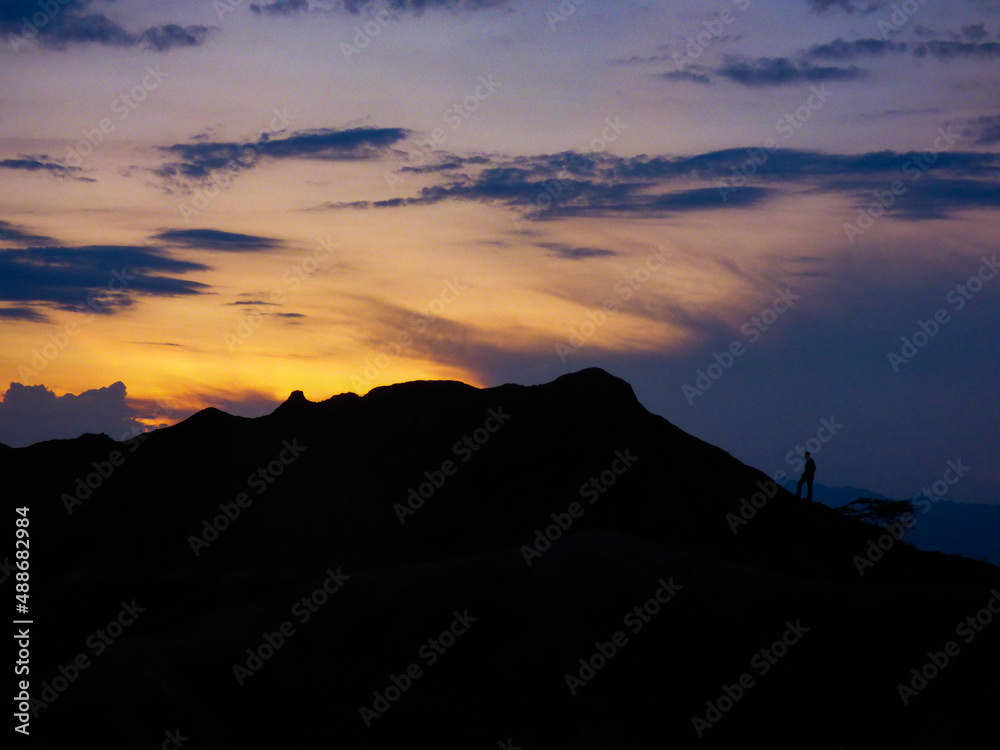 Man walking on top of a mountain looking at the sunset
