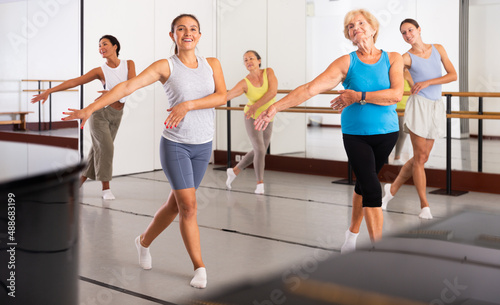 Dancing active women engaged in a group class practice energetic dance in a modern dance studio