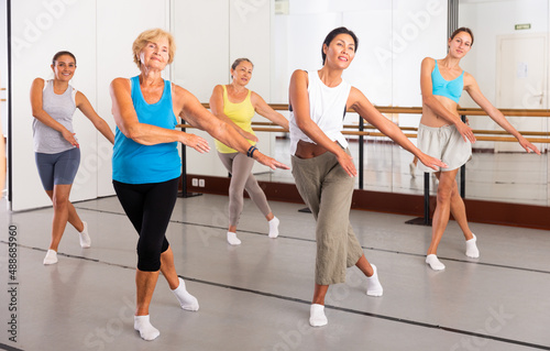 Group of active women practicing energetic dance in a modern dance studio
