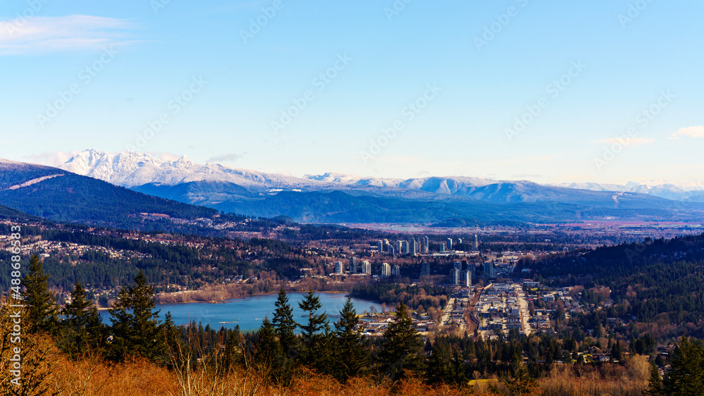 Late winter view of Burrard Inlet at Port Moody, BC,  with alpine mountain backdrop and buds just beginning to show on trees in foreground.