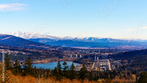 Late winter view of Burrard Inlet at Port Moody, BC, with alpine mountain backdrop and buds just beginning to show on trees in foreground.