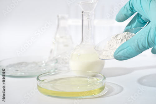 medical laboratory research, petri dish with growth medium and powder substance in a hand. glassware on a table in a lab. drugs development and testing.