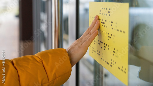 Close-up of a woman reading a braille lettering on a glass door. photo