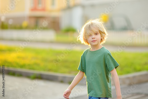 Cheerful little boy enjoying warm sunny summer day of holidays. Active child playing on the street of small town. Freedom, rest, vacation and childhood concept. © Maria Sbytova