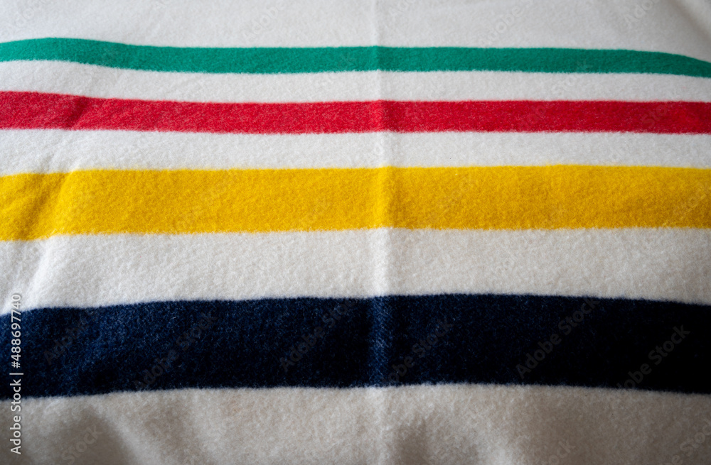 Detail of a bay blanket with green, red, yellow and blue stripes. Detail of a bay blanket with green, red, yellow and blue stripes.