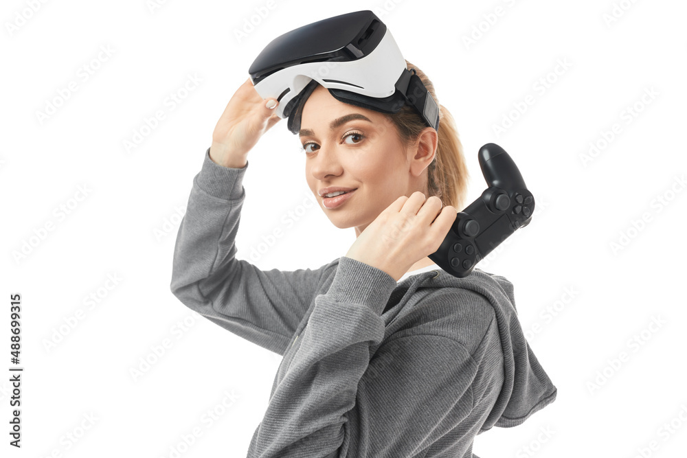 Happy young lady with VR headset and controller looking at camera in studio Happy young lady with VR headset and controller looking at camera in studio