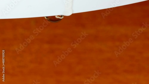 Macro shot of drops of water falling from  a white border into a wood surface photo