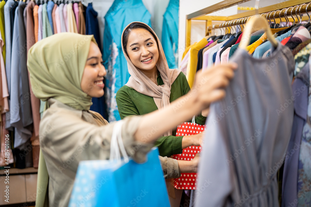 muslim female friend buying new dress at fashion store