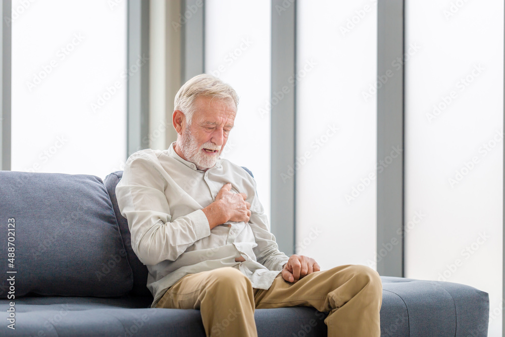 Senior man presses hand to chest has heart attack suffers from unbearable pain, Man with pain on heart in living room