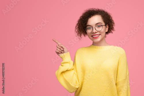 Content young lady pointing away in pink studio