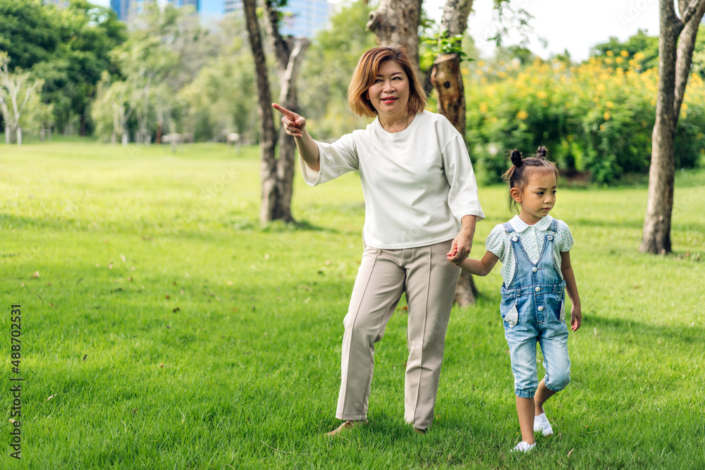 Portrait of happy love asian grandmother and little asian cute girl enjoy relax in summer park.Young girl with their laughing grandparent smiling together.Family and togetherness