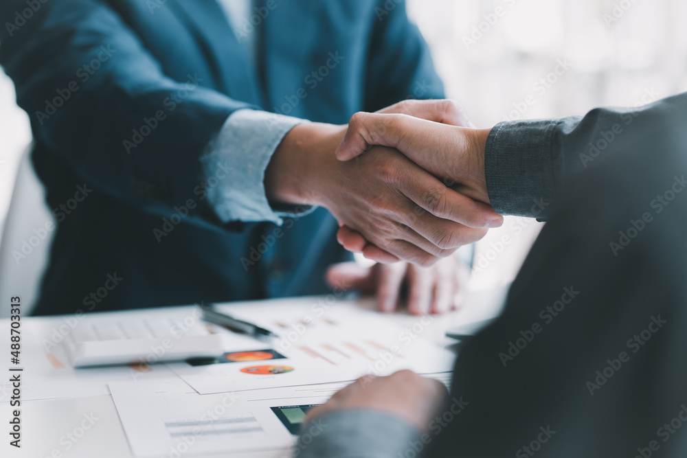 Good deal. Close-up of two business people shaking hands while sitting at the working place Good deal. Close-up of two business people shaking hands while sitting at the working place