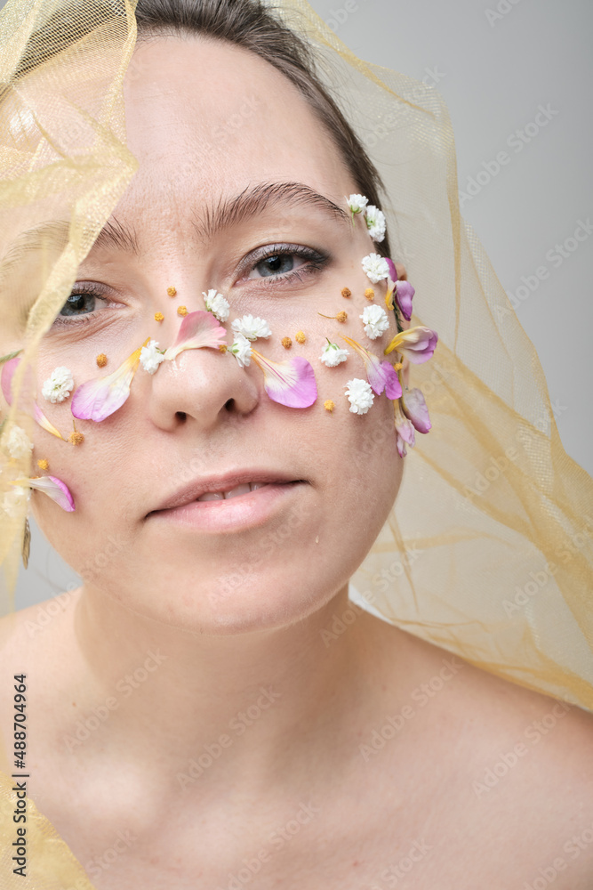 Beautiful woman with flowers on her face, conceptual photo. The idea of femininity and spring