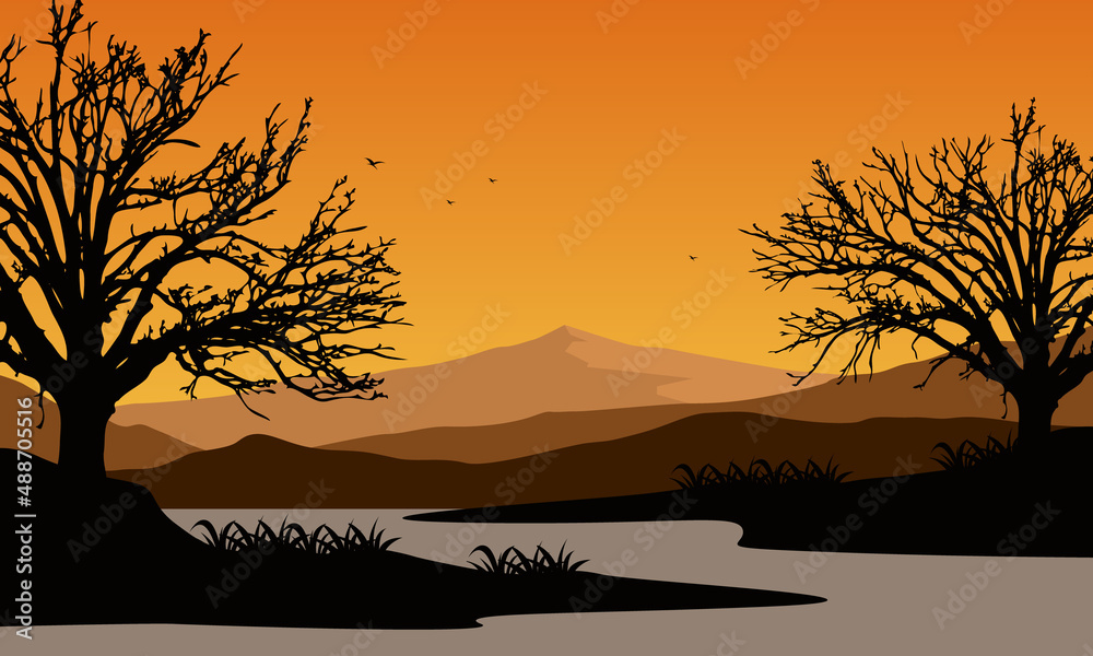 The beautiful mountain view from the riverside with the silhouette of dry trees around it