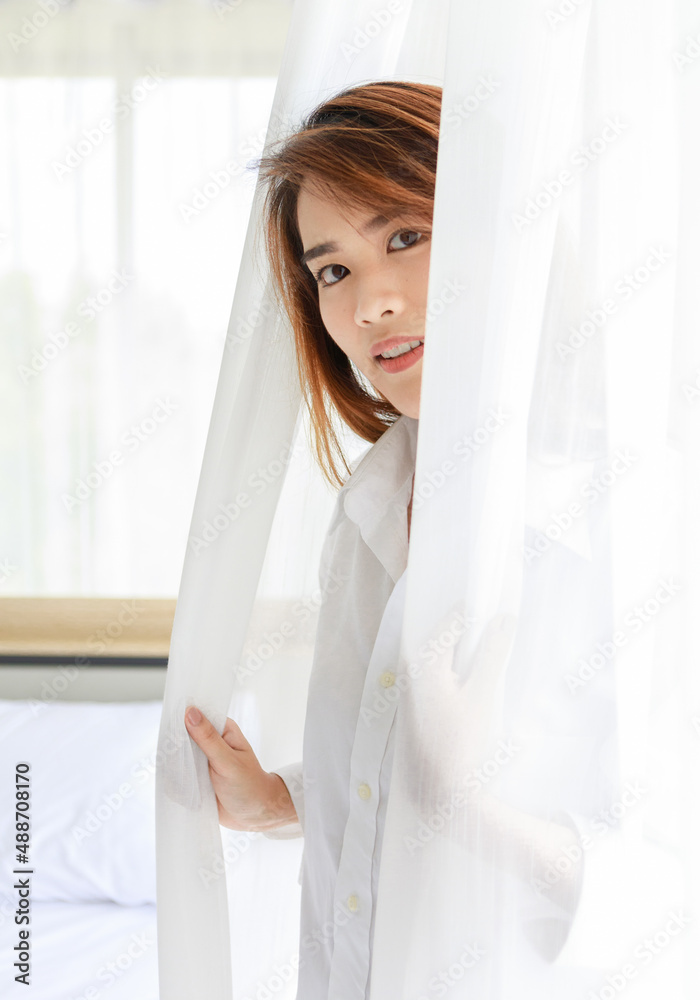 Unrecognizable unknown young long brown hair lazy female model in white shirt pajamas sitting on bed with pillows and blanket in bedroom waking up in early morning holding hands stretching arms Unrecognizable unknown young long brown hair lazy female model in white shirt pajamas sitting on bed with pillows and blanket in bedroom waking up in early morning holding hands stretching arms