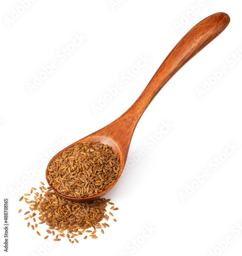 Roasted cumin seeds in the wooden spoon, isolated on the white background.