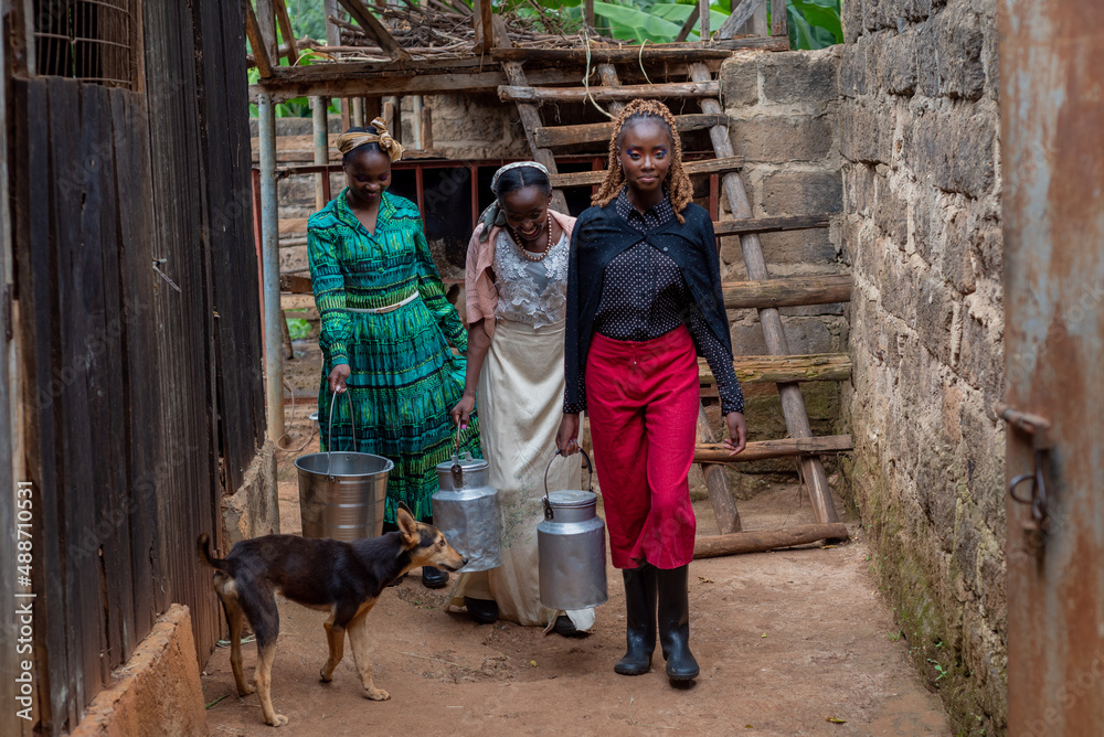 Three young african women carrying milk containers Three young african women carrying milk containers