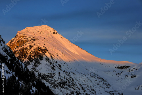 Snowy mountain lit by dawn sun during sunset, British Columbia, Canada.