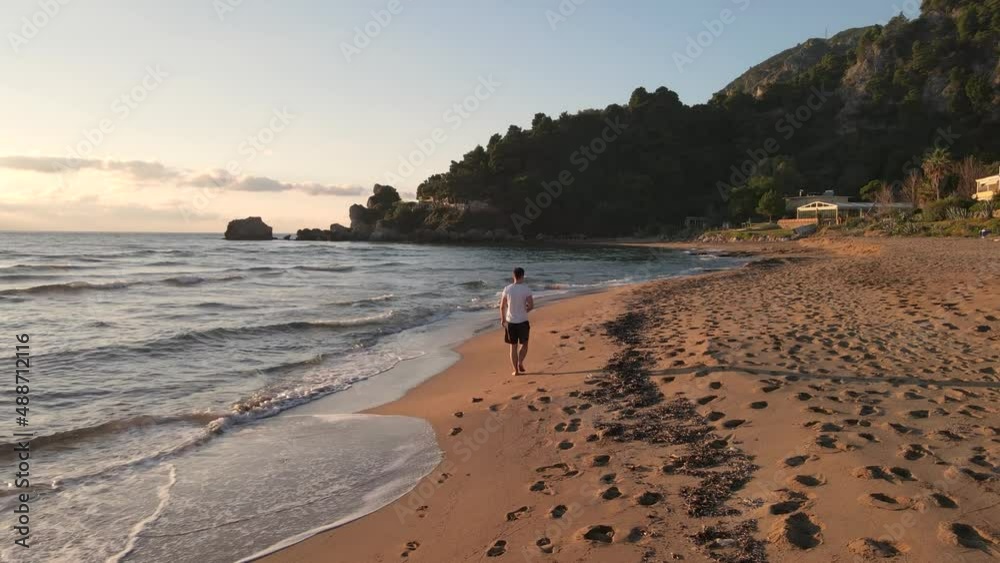 Lonely man walking on an empty beach, close to the water at sunset time. Lonely man walking on an empty beach, close to the water at sunset time.