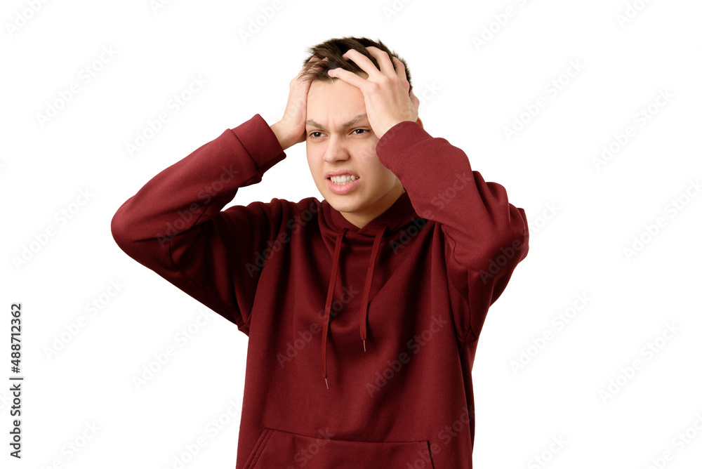 Shocked teenager feeling despair holding his head in his hands, isolated on white background. Angry frustrated young guy having troubles. Negative emotions.