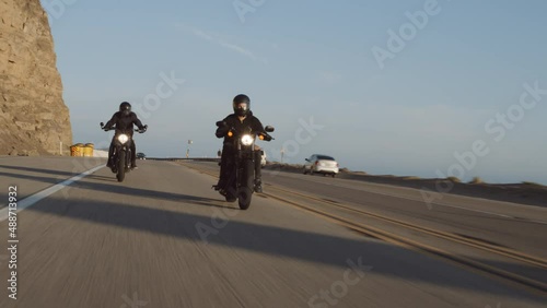 Astonishing scenery of fast bikers driving black motorbikes with coastal vista on a route. Pacific road trip concept. People enjoy high speed, while riding their bikes. High quality 4k footage