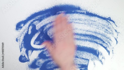 Write 2023 on blue sand year. Painting in the sand. Draw with your hands on the croup. Hand drawing. Erase text by hand. wash photo