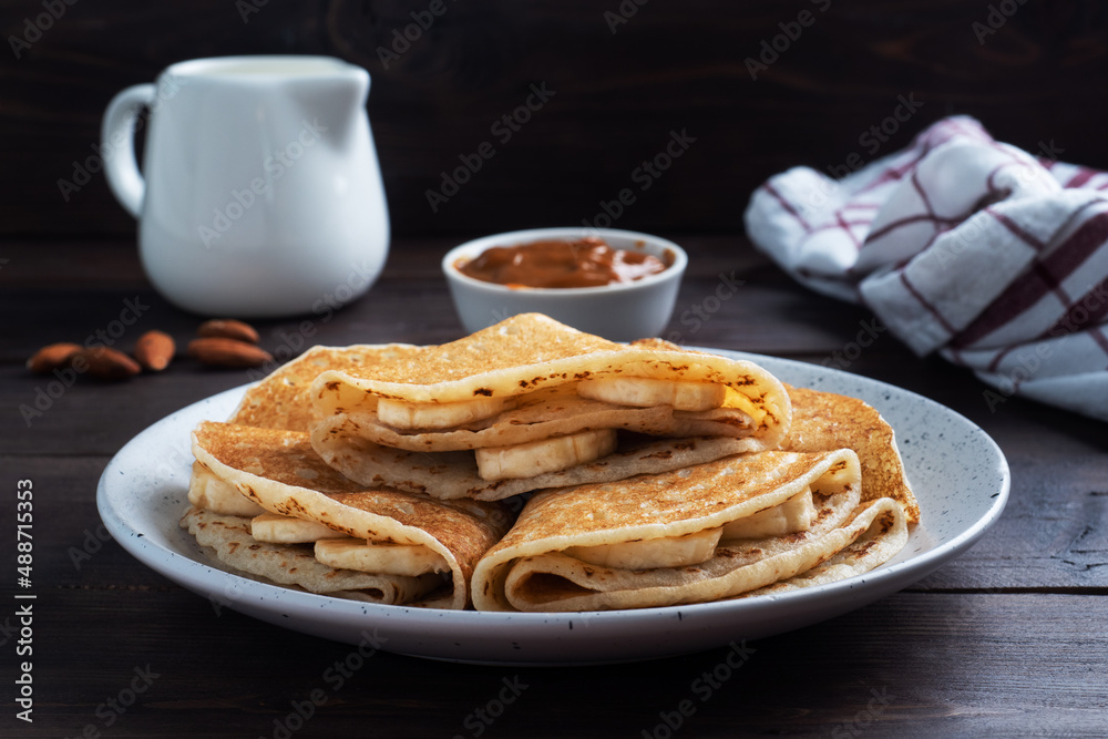 Pancakes with chocolate banana filling. Wooden rustic table, sweet delicious dessert.