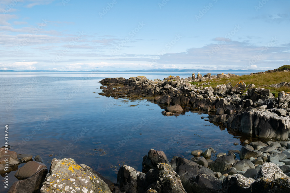 Rock on the shore along the coast of the island of Islay with beautiful blue and clam water on a sunny summer day