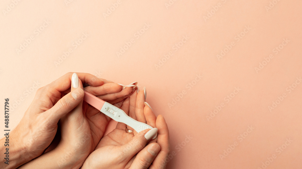 Pregnancy test positive. Female hand hold positive pregnant test with silk ribbon on pink background. Medical healthcare gynecological, pregnancy fertility maternity people concept. - obrazy, fototapety, plakaty 