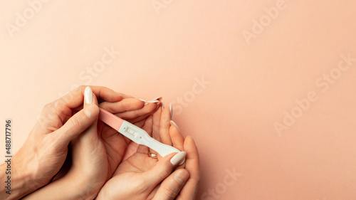 Pregnancy test positive. Female hand hold positive pregnant test with silk ribbon on pink background. Medical healthcare gynecological, pregnancy fertility maternity people concept. photo