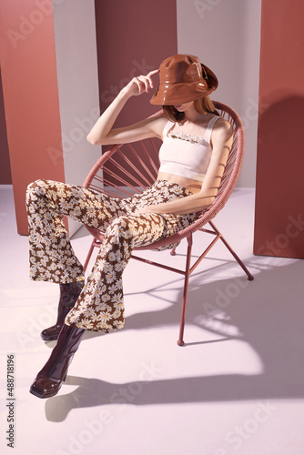 High fashion spring portrait of young elegant woman in retro outfit. Retro pants, panama hat, leather boots, flowers. 60s, photo