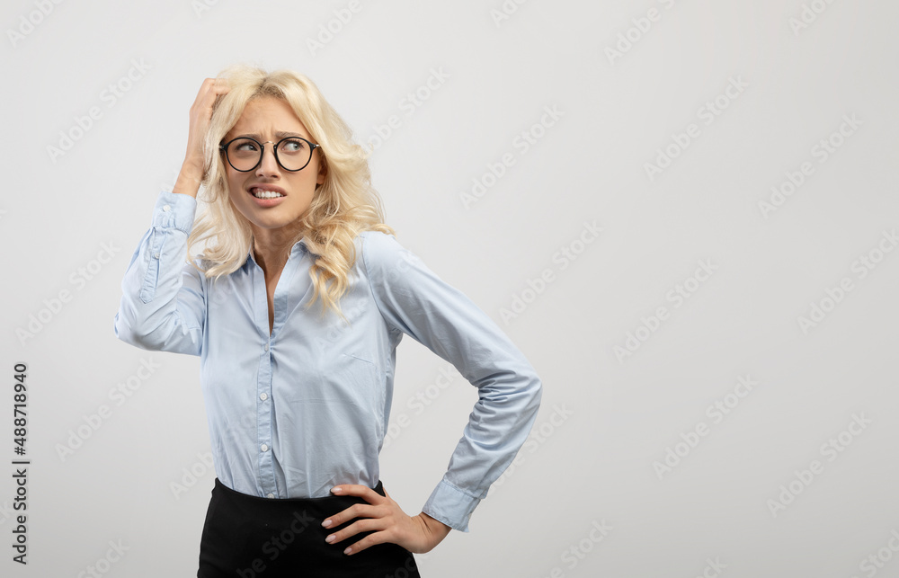 Young doubting businesswoman thinking and touching head, looking aside at free space, light grey studio background Young doubting businesswoman thinking and touching head, looking aside at free space, light grey studio background