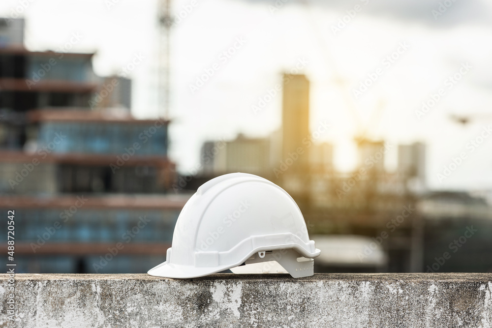 Close up shot White safety helmet hard hat put near modern building construction view. Civil engineer concept. Close up shot White safety helmet hard hat put near modern building construction view. Civil engineer concept.