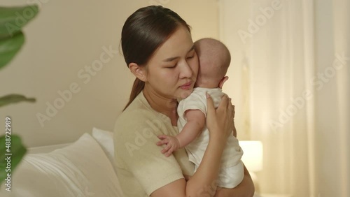 Young Asian mother with her newborn baby crying and scream with colic problem at night photo