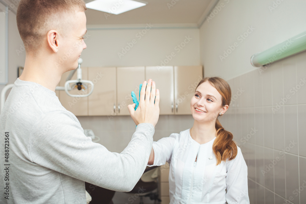 Beautiful female dentist in office in clinic, satisfied happy client shakes hands, excellent professional service. hand to hand
