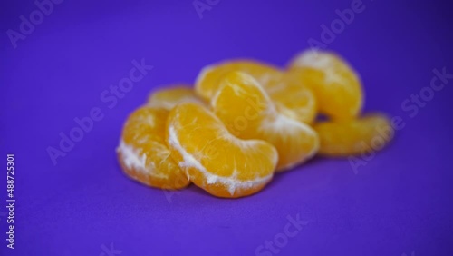peeled and split mandarins against a lilac background, the camera gently swings around the tangerines